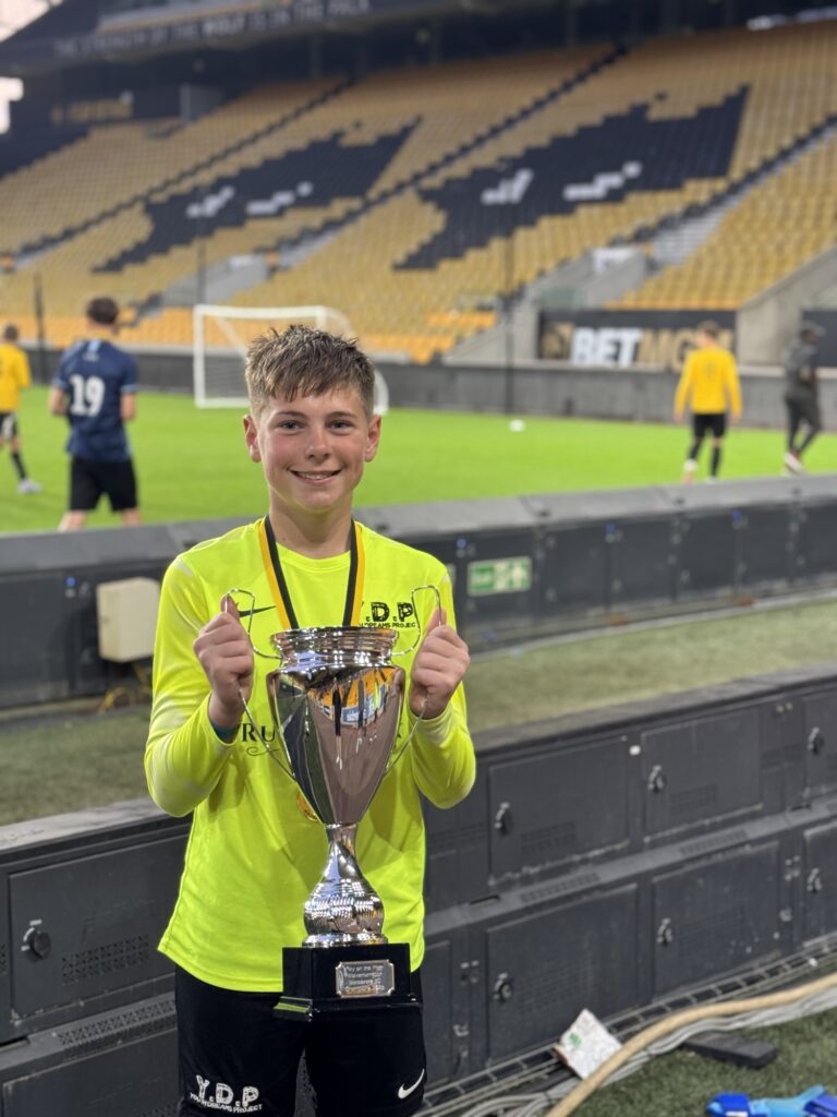 JB1 lifts the U13 winners trophy for play on the pitch at Wolverhampton Wanderers FC